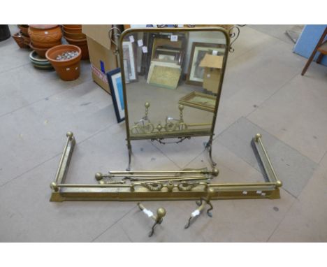 A brass fender, a brass companion set, a pair of brass fire dogs and a brass mirrored firescreen