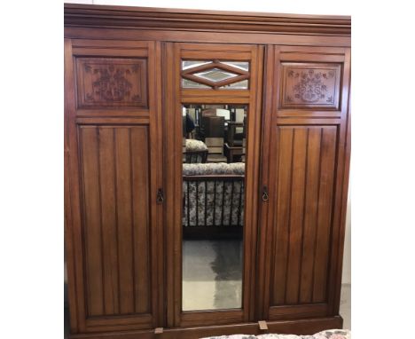 A vintage mahogany triple Gentleman's wardrobe with carved detail to doors and bevel edged mirrors. Interior has hanging rail