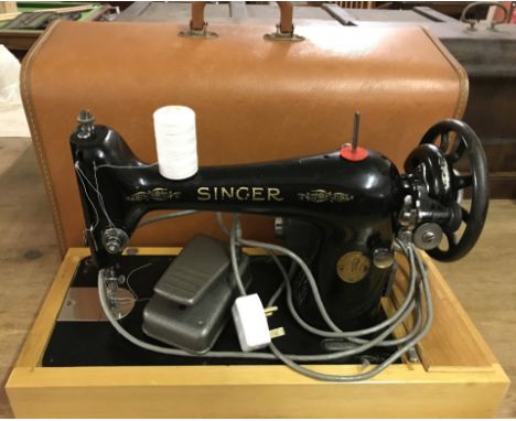 A vintage cased Singer sewing machine with electric motor and foot pedal.  