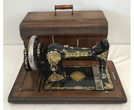 A vintage wooden cased Jones sewing machine with boxed accessories.  