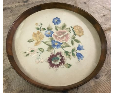 A vintage dark wood framed circular tray with glass covered floral design needlepoint base.  Approx. 40cm diameter.