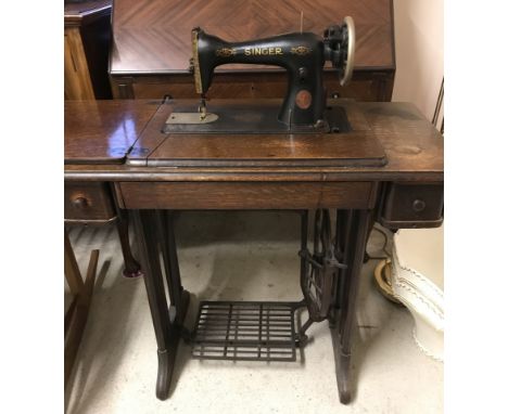 A vintage wooden framed Singer treadle sewing machine with lift up lid. 2 drawers and pull down thread compartment. Complete 