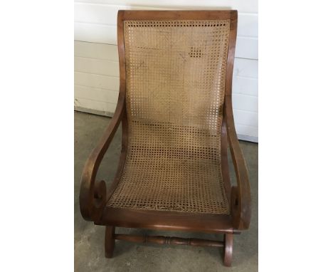 A vintage cane seated low easy chair with scroll design arms. Some damage to cane seat at front. 