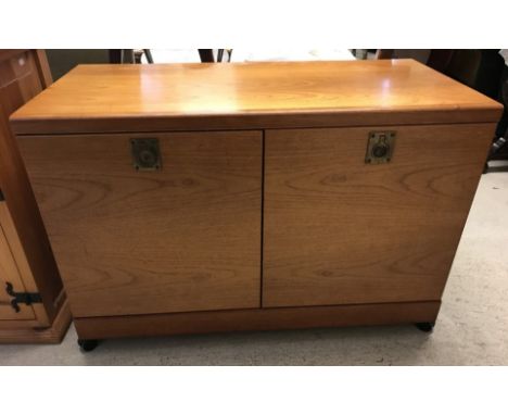 A modern low 2 door oak cupboard with interior shelf, on castors. With flush brass handles. Approx. 92cm wide x 61cm tall.