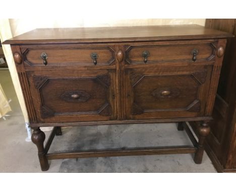 A dark oak vintage 2 door, 2 drawer side board with carved detail to front and legs. With drop down handles and baize lined c