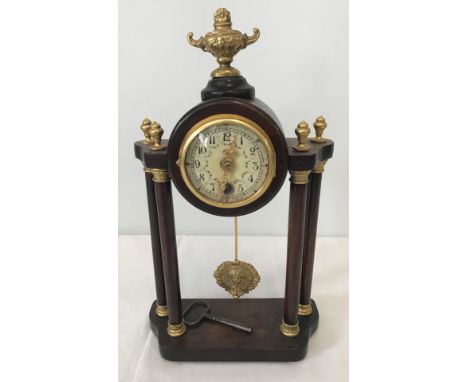 A modern reproduction Portico style 4 column mantel clock. With hanging pendulum and gilt coloured finials. Complete with key