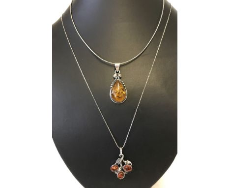 An Art nouveau style amber set pendant together with a modern design amber set pendant marked 925. Both pendants on white met