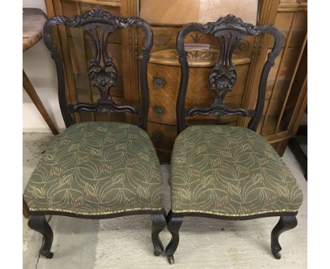 A pair of Victorian mahogany nursing / bedroom chairs with ornate carving to chair backs. On cabriole style front legs and ce