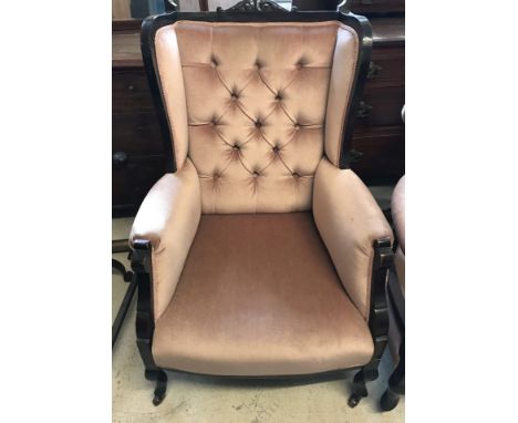 A late Victorian button backed wing chair with dusky pink velvet upholstery. On ceramic castors and with carved detail to top