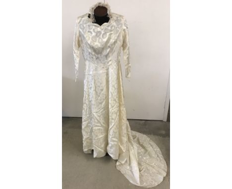 A 1955 handmade wedding dress with head dress and underslip. Some staining to both underslip and dress. Long sleeves with cov