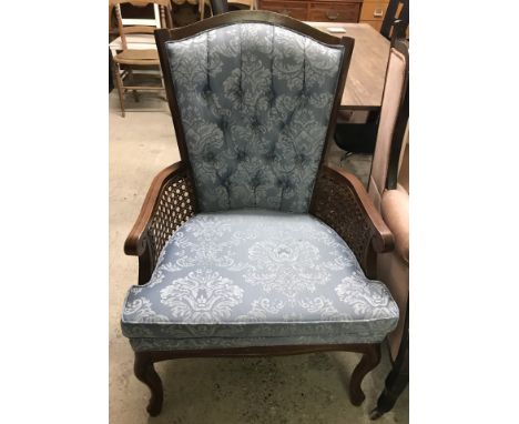 A dark wood framed armchair with cane backing and blue button back upholstery. Cabriole style front legs. 