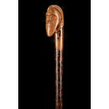 AN ANTIQUE FOLK ART CANE, the fruitwood handle carved with moustached man's head on ebonised