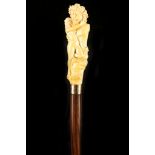AN ANTIQUE IVORY HANDLED CANE, depicting a smiling Bacchus in an embrace with a naked female figure,
