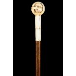 AN EROTIC JAPANESE MEIJI PERIOD IVORY HANDLED WOODEN CANE, the spherical grip carved with faces