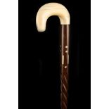 AN IVORY HANDLED WALKING CANE, the hook grip mounted to an ivory inlaid shaft with carved twist