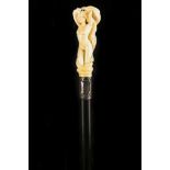 A FIGURAL ANTIQUE IVORY HANDLED CANE, the grip carved with a naked maiden clad with snakes, sterling