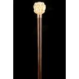 AN ANTIQUE JAPANESE NOH MASK IVORY HANDLED CANE, the grip carved with many faces over 9ct gold