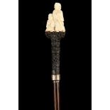 A 19TH CENTURY ORIENTAL MARINE IVORY AND EBONY HANDLED CANE, the top with two figures on carved body
