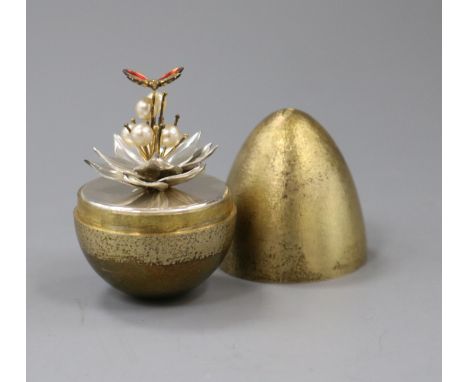A silver-gilt 'surprise' egg by Stuart Devlin, opening to reveal an enamelled butterfly resting on a silver flower with pearl