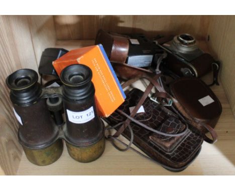 A shelf of camera equipment, pair of binoculars and a cased Rolls Razor