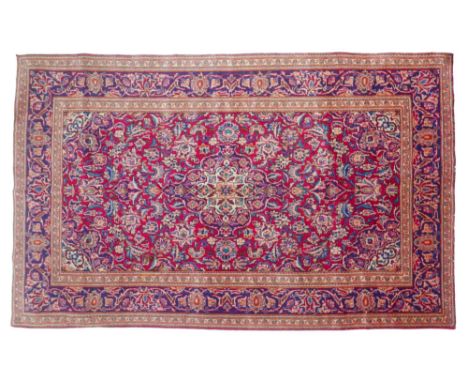 A Kashan rug, with red ground, light and dark blue, cream and red foliate and floral decoration, 215 by 123cm. 