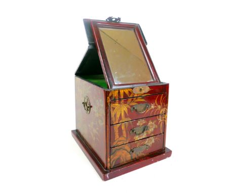 A Chinese red lacquer jewellery/dressing chest with a folding mirror above three drawers, 26cm wide by 34 cm by 28 cm tall.So