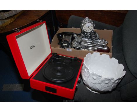 A clock and a telephone and a small suitcase, record players and a jardiniere.