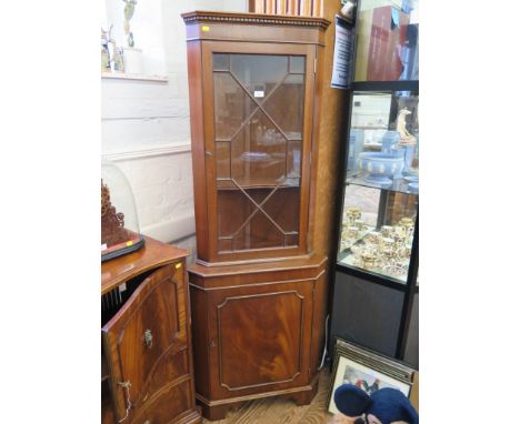 A mahogany veneered corner cabinet with astragal glazed door over a panelled door on bracket feet