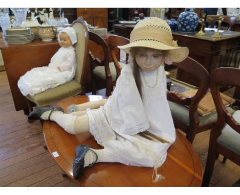 A mannequin of a seated child wearing a straw hat and pearls, and a plaster doll (2)