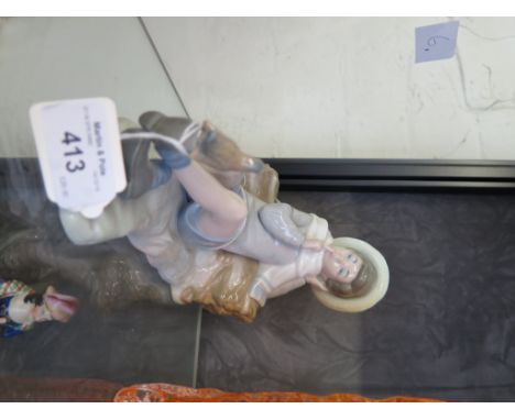 A Lladro figure of a boy reclining and hushing a bird, 22cm long