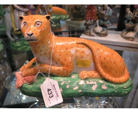 An early 19th Century Staffordshire figure of a seated leopard, with meat under its front paws, on a green naturalistic base,