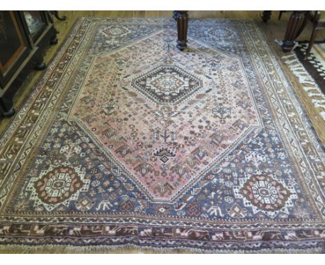 A Turkoman carpet, the faded red field with brown diamond medallion and blue spandrels all filled with geometric floral motif