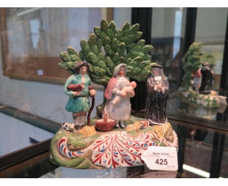 An early 19th Century Staffordshire Tithe Pig Group, with tree bocage and red and blue scroll base, in the manner of John Wal