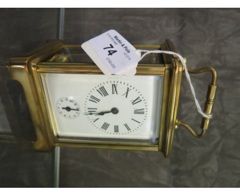 A brass carriage clock, of conventional design with oval glass top plate and enamel dial with subsidiary alarm dial, the twin