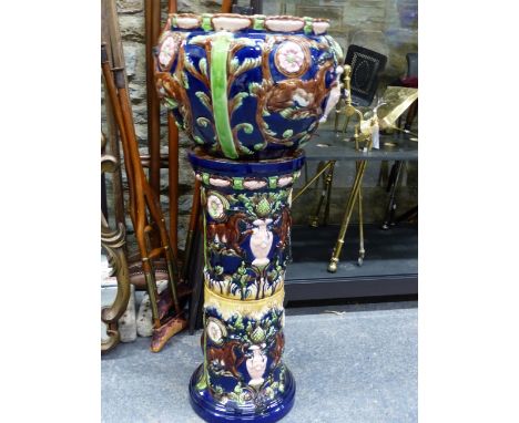 A LATE 19th C. MAJOLICA PLANTER AND STAND DECORATED IN RELIEF WITH PAIRS OF FANTASTIC CAT CREATURES FLANKING PINK VASES OF FO