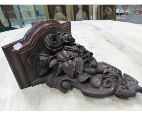 A VICTORIAN PIERCED AND CARVED OAK WALL BRACKET, THE SHELF ABOVE A SCROLLING SHIELD SHAPE WITH ROSES AND FOLIAGE RAISED BEFOR