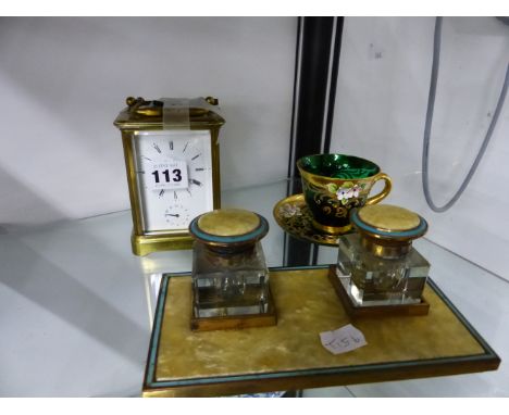 A VINTAGE BRASS CASED CARRIAGE CLOCK WITH ALARM, A DESK STAND, AND AN ENAMELLED GLASS CUP AND SAUCER. 