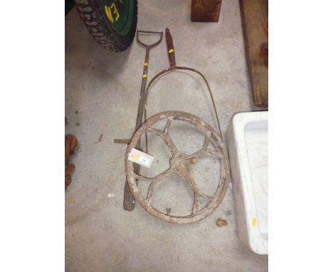 An old ornate barrow wheel, barley straw pitch fork end and a trench/ditching tool