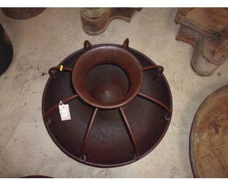 A large round cast iron pig trough with dividers