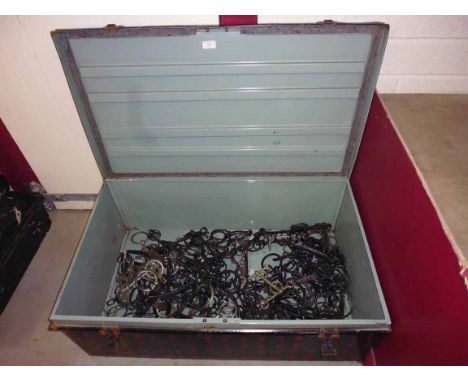 A large metal harness trunk containing a large quantity of horse bits including some unusual examples