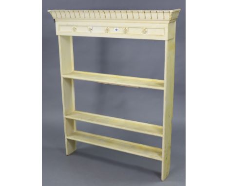 A set of light cream painted wooden wall shelves with a moulded frieze, &amp; fitted three open shelves, 37¾” wide x 46½” hig