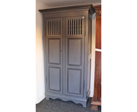 A continental-style blue/grey painted wooden two-door wardrobe with a moulded cornice, enclosed by a pair of fielded &amp; pi