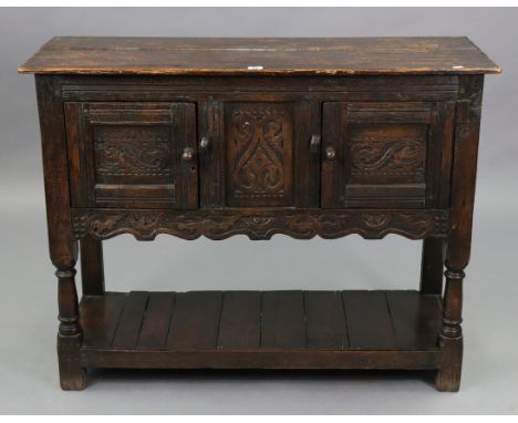 A 17th century-style oak livery cupboard enclosed by a pair of carved panel doors to either side, with a carved panel to cent