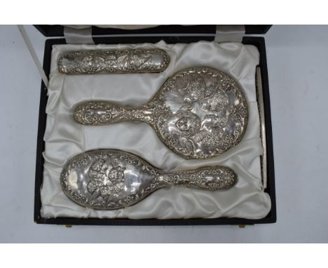 A cased silver dressing table set in the Reynold's Angels design to consist of a hand mirror, comb and two brushes (4). Birmi