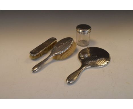 Assorted silver-mounted dressing table items comprising silver-lidded jar, hand mirror, hand brush and clothes brush, all wit