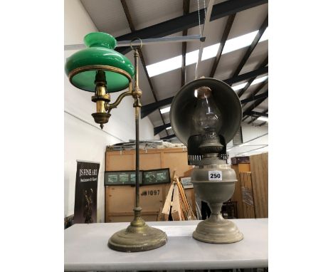 AN OIL LAMP WITH A METAL REFLECTOR SHADE TOGETHER WITH A TABLE LAMP ADJUSTABLE ON A COLUMN AND WITH A GREEN GLASS SHADE