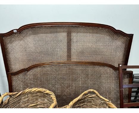 A PAIR OF KING SIZE CANED BED ENDS BY HEAL AND SON, LONDON. WITH IRON SIDE RAILS.
