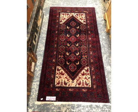 AN EASTERN HAND WOVEN RED GROUND SMALL CARPET 186 X 97CMS. 