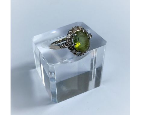 A yellow metal dress ring set central peridot surrounded by 14 diamonds, stamped '14K', 3.9 gm Diamonds are well matched, the