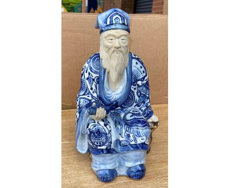 A Chinese figure of a seated man with beard in blue and white glazed robes, impressed mark to base, height 30cm (1 hand a.f.)